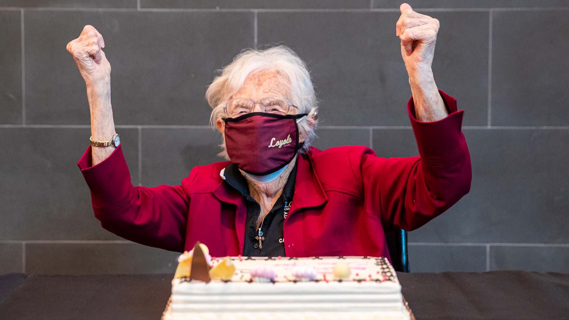 Sister Jean celebrating in front of a 102-decorated birthday cake